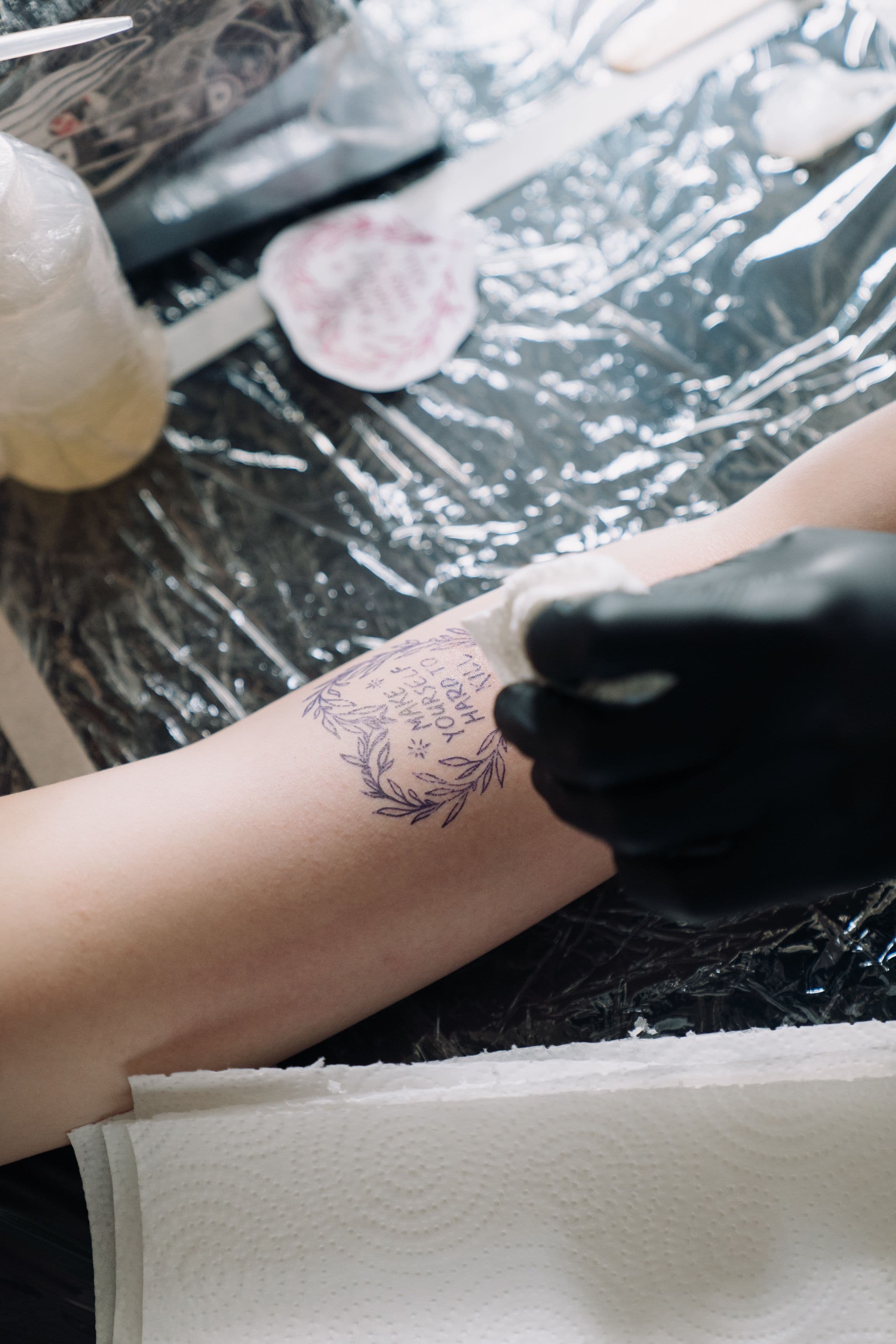 Laurel and quote tattoo stencil placed on an arm